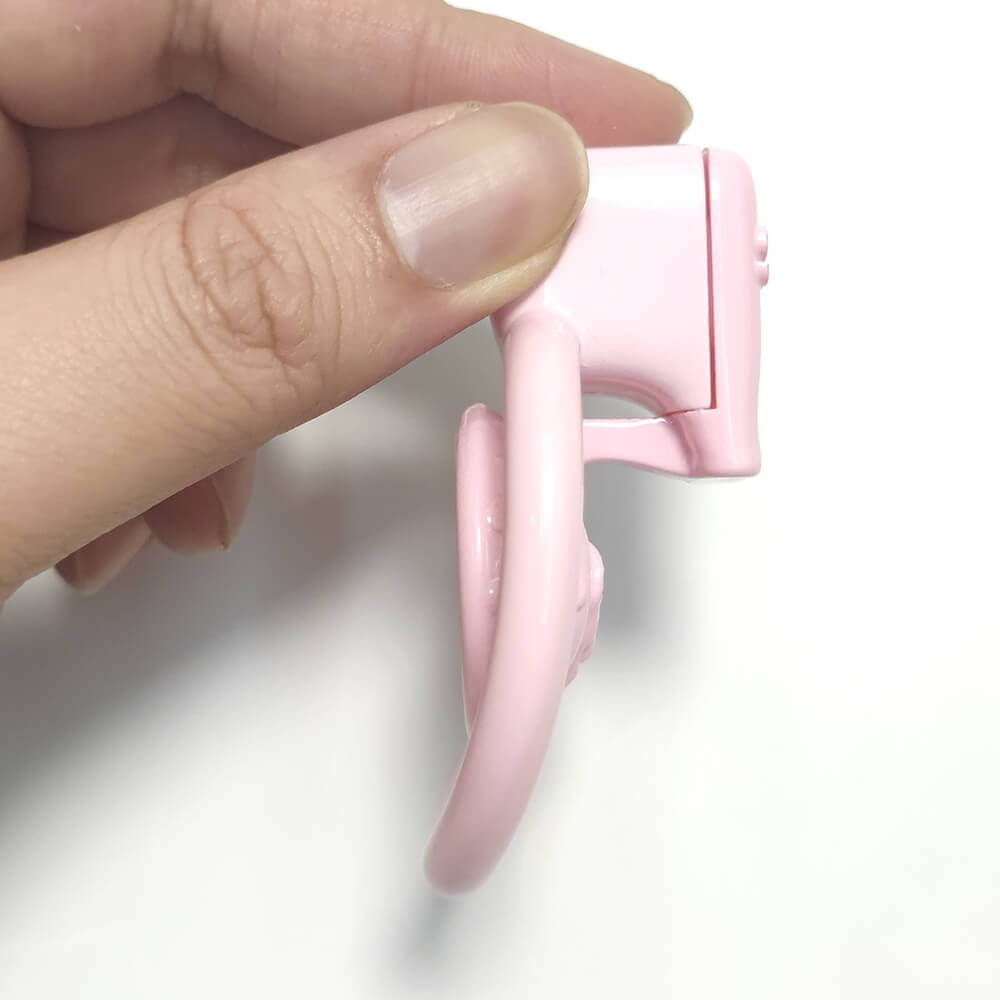 Pink compact chastity cage held by hand to show side depth
