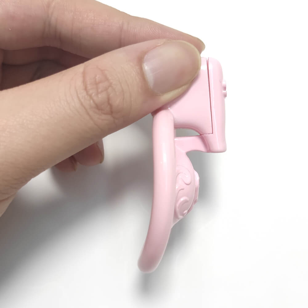 Hand-held pink chastity cage with a short curved profile
